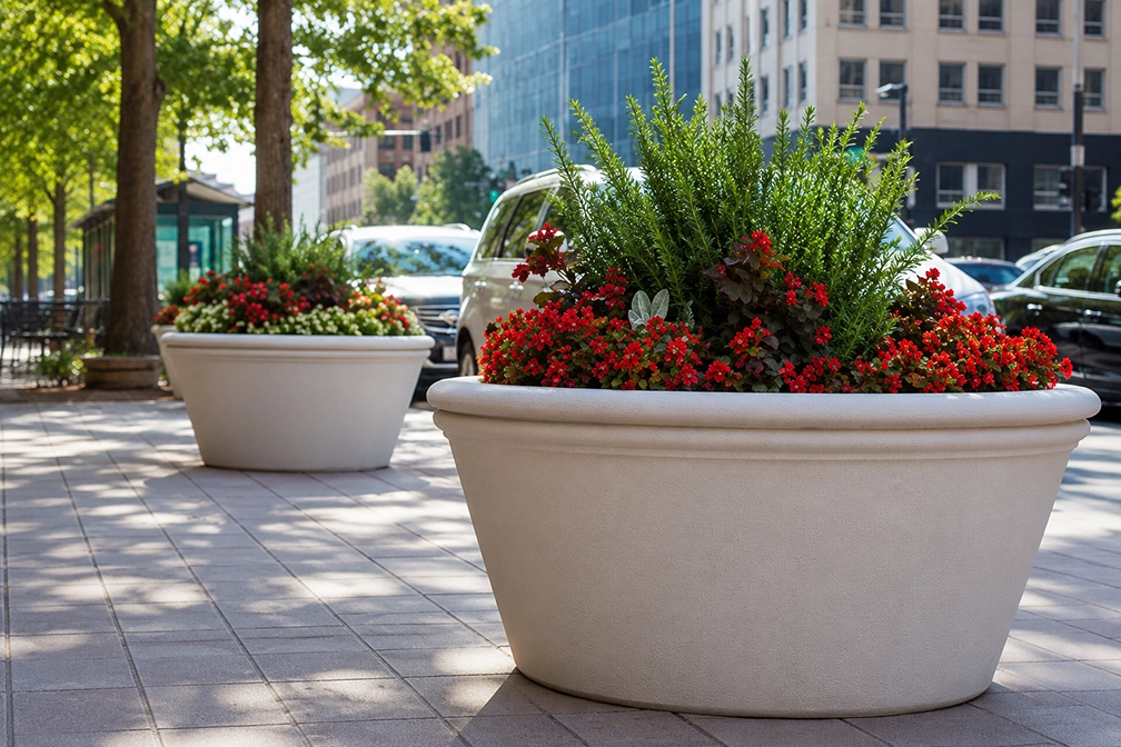 Large commercial planters with colorful flowers and greenery defining a pedestrian walkway in an urban setting